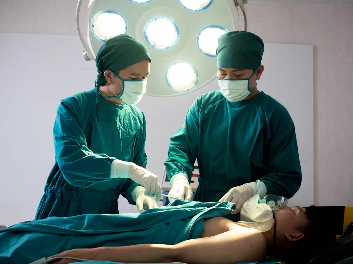 Deux médecins en blouses vertes dans un bloc opératoire qui prend soin d'un patient allongé sur un lit